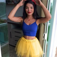 a woman in a blue top and yellow skirt posing for the camera with her hands on her head