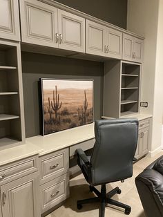 an office with white cabinets and gray leather chair