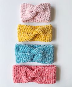 three crocheted headbands in different colors on a white surface, one with a bow