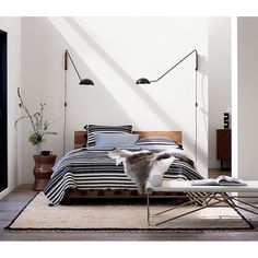 a bed with black and white striped sheets in a room next to a wall lamp