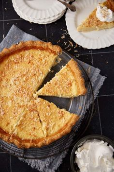 a pie sitting on top of a table next to two plates with slices missing from it