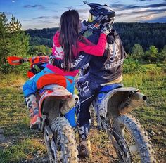 two people riding on the back of dirt bikes