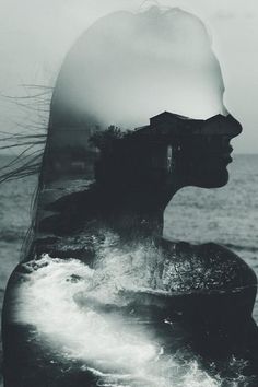 a woman's face is reflected in the water with her hair blowing in the wind