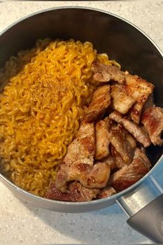 a pan filled with meat and noodles on top of a counter next to a spatula