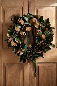 a wreath is hanging on a door with green ribbon and leaves attached to the front