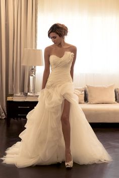 a woman in a wedding dress is posing for the camera with her foot on the bed