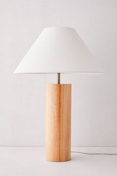 a wooden table lamp with a white shade on the base and a light bulb attached to it