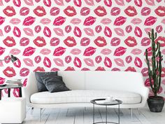 a white couch sitting in front of a wall with pink lipstick prints on it's walls