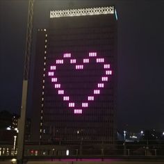 a large building with a heart on it's side in the dark night time