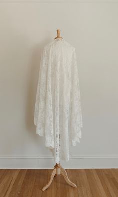 a white lace dress on a mannequin stand in front of a plain wall