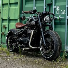 a black motorcycle parked next to a green shipping container