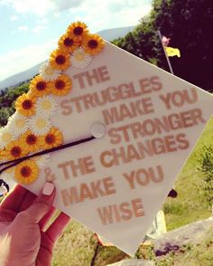 someone holding up a graduation cap with flowers on it