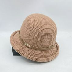 a tan hat with a brown band on top of it, sitting on a white surface