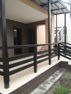 a balcony with black railings next to a brick wall and grass on the ground