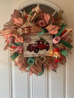 a christmas wreath with an old red truck on it and ribbon around the front door