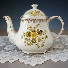 a white tea pot with yellow flowers painted on it