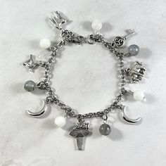 This Artemis, Selene, and Hecate themed charm bracelet is the perfect accessory to showcase your love for the Greek goddesses associated with the moon. Charms included: Stag - a symbol of Artemis Bow and Arrow - a symbol of Artemis Crecsent Moon Torch - a symbol of all three  Creacent Moon Bull - a symbol of Selene Key - a symbol of Hecate  Moonstone and labradorite gemstone beads are included in between each charm. Comes in three sizes: Small: 6.5 inches (with extra rings at the end to expand u Artemis Jewelry, Metal Charm Bracelet With Moon Charm As A Gift, Hekate Jewelry, Silver Metal Bracelets With Moon Charm, Silver Metal Bracelet With Moon Charm, Hekate Necklace, Celestial Bracelet With Moon Charm, Artemis Jewelry Moon Goddess, Moon Goddess