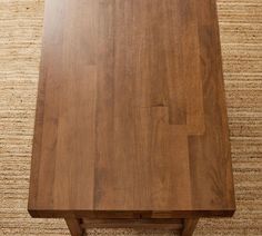 a wooden table sitting on top of a carpeted floor next to a brown rug