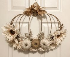 a wreath with sunflowers and leaves hanging on a door