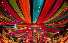 the interior of a decorated tent with bright colored draping on it's ceiling