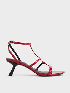 Even the slightest heel can make a significant difference to your posture. Elevate both your style and stature with these Clara asymmetric T-bar sandals. They feature a classic T-bar design with a contemporary twist -- additional straps create a stylish cage-like effect that lends a cool edge to the elegant design. The glossy red finish adds a sensual appeal and will infuse your outfit with a touch of fierce elegance Modern Red Sandals With Single Toe Strap, Evening Sandals With Sculpted Heel And T-strap, Evening T-strap Sandals With Sculpted Heel, Evening T-strap Sandals With Heel Loop, Chic T-strap Sandals With Padded Heel, Modern T-strap Sandals For Evening In Spring, Modern Red Evening Sandals, Modern T-strap Heels For Summer, Modern T-strap Heels For Evening