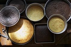 several pans filled with different types of cake batter on top of a wooden table