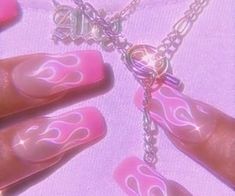 pink and silver items are hanging from chains on a white surface with light shining in the background