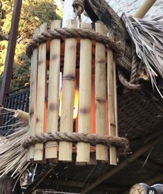 a wooden light hanging from the side of a building next to some plants and trees