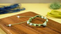 a wooden board topped with two bracelets on it's sides and beads hanging from the ends