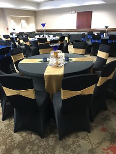 a banquet room set up with black chairs and gold tablecloths