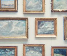 many paintings are hanging on the wall with gold frames and blue sky is in the background