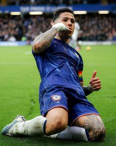 a soccer player sitting on the ground with his hand up to his face and one eye open