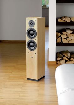 a pair of speakers sitting on top of a wooden floor next to stacks of logs