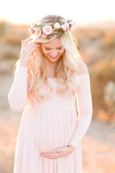 an image of a pregnant woman wearing a flower crown and holding her hands on her head