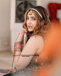 a woman with makeup painted on her face is sitting and posing for the camera while wearing an elaborate head piece