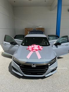 a gray car with a pink bow on the hood