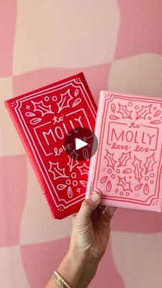 a person holding up a pink and red box with the word moly on it