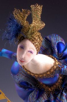 a doll is dressed in blue and gold with an elaborate headpiece on it's head