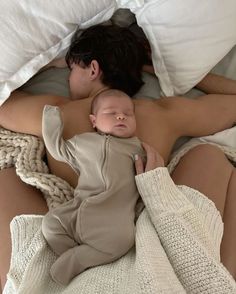 a man and woman laying in bed with a baby sleeping next to eachother