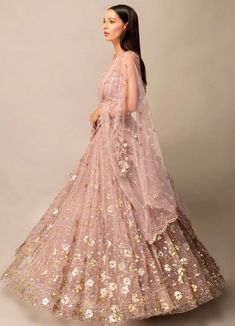 Step into the spotlight with this Lavender Pink Gold Sequinned Lehenga Set. The tulle fabric beautifully showcases hand-embroidered mirror flower motifs that add a touch of sparkle. Complete with a filly embellished blouse and a delicate tulle dupatta featuring a statement scalloped border, this set is the epitome of elegance and glamour. Composition: Lehenga, Dupatta and Blouse - Soft Tulle All products can be customised for sleeves, length of blouse and neck design Delivery : 4-6 weeks as the product is hand crafted. Check Size Guide or choose MySize for free customisation (All Sizes above XL can be made at 15% additional cost) For more information and sizes please contact fabiliciousfashion@gmail.com or visit our Copenhagen studio. Navratri Embellished Organza Lehenga, Navratri Reception Gown With Sequins, Sequin Gown For Reception And Navratri, Party Wear Embroidered Tissue Silk Lehenga, Fitted Net Gown With Resham Embroidery, Fitted Bollywood Net Gown, Navratri Sequin Floor-length Gown, Wedding Saree With Embroidered Sequins, Pink Net Dresses For Designer Wear