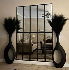 a mirror that has some black feathers on it in the middle of a living room