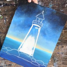 someone is drawing a lighthouse on a piece of paper with colored pencils and watercolor paints