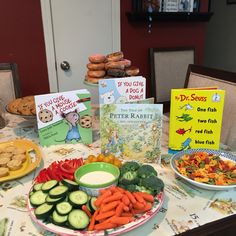 a table filled with lots of food and books on it's sides, including carrots, cucumbers, broccoli, bread