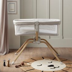 a white baby crib sitting on top of a wooden floor next to a rug