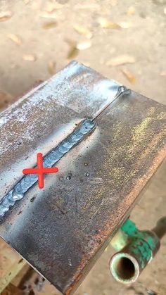 a piece of metal sitting on top of a table with a red cross painted on it