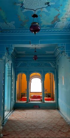 an empty room with blue walls and red couches in the center, under a painting on the ceiling