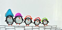 a group of penguins wearing hats on top of a wire fence in front of a white wall