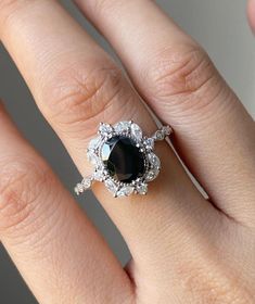 a woman's hand with a black and white diamond ring on top of it