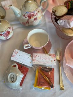 a table topped with tea cups and plates filled with food