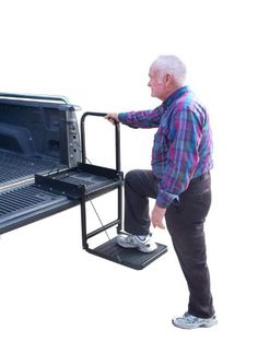 an older man standing next to a microwave with the door open and his feet propped up